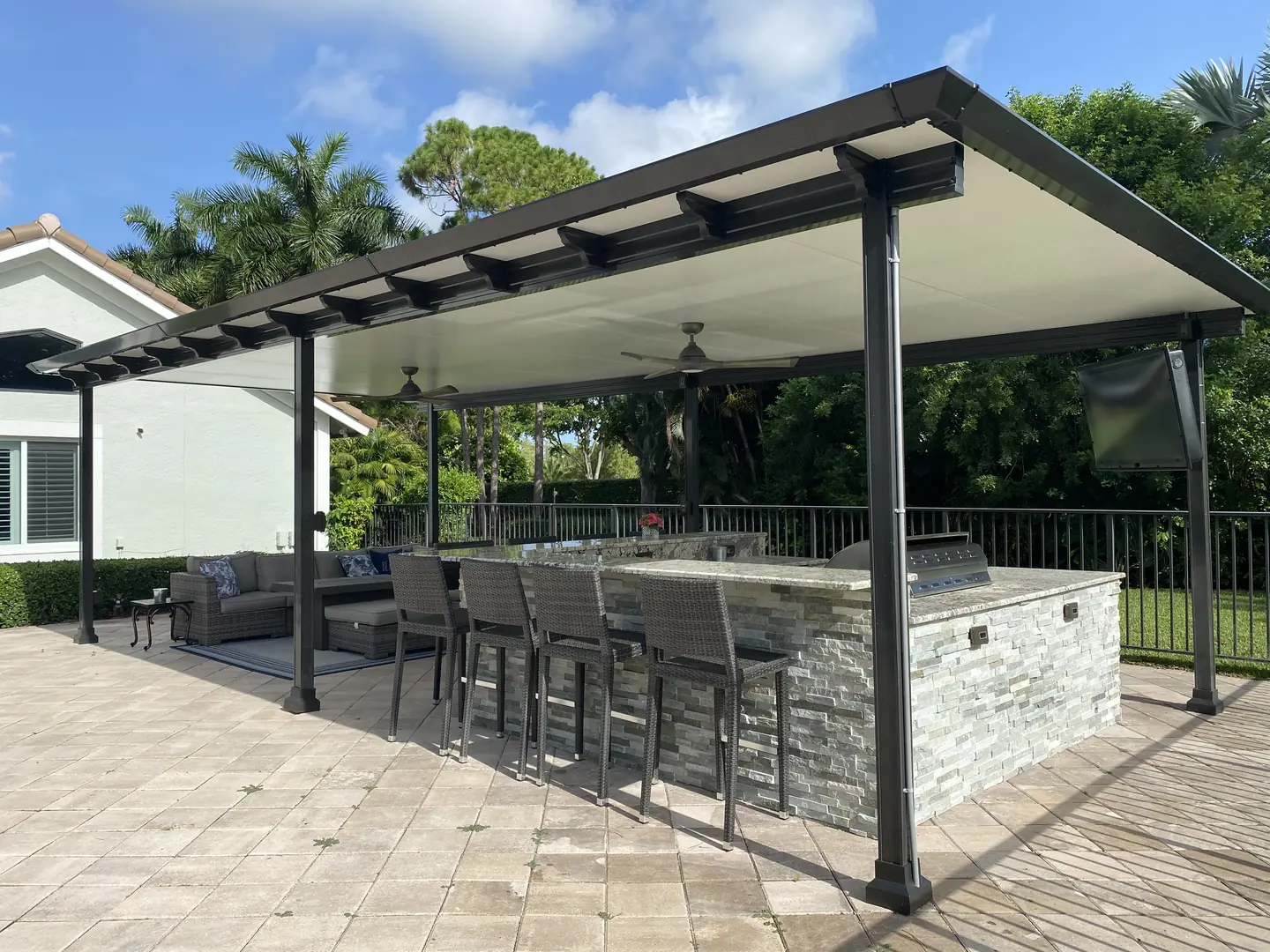 Covered outdoor kitchen and lounge with pergola beside a pool