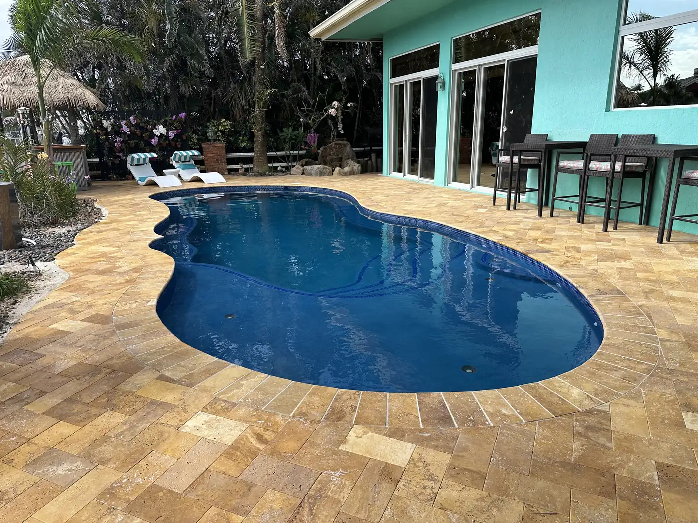 Outdoor living space with pool deck, lounge seating, and landscaping