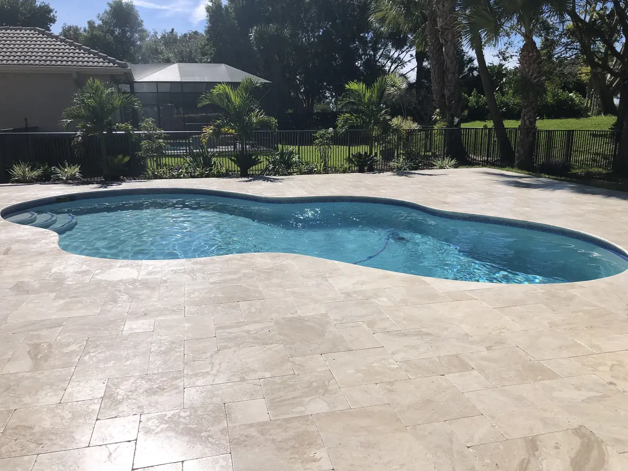 Luxury freeform swimming pool with travertine deck